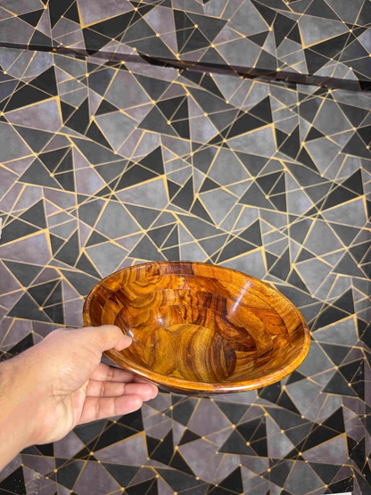 Wooden serving bowl held to show its shape and grain