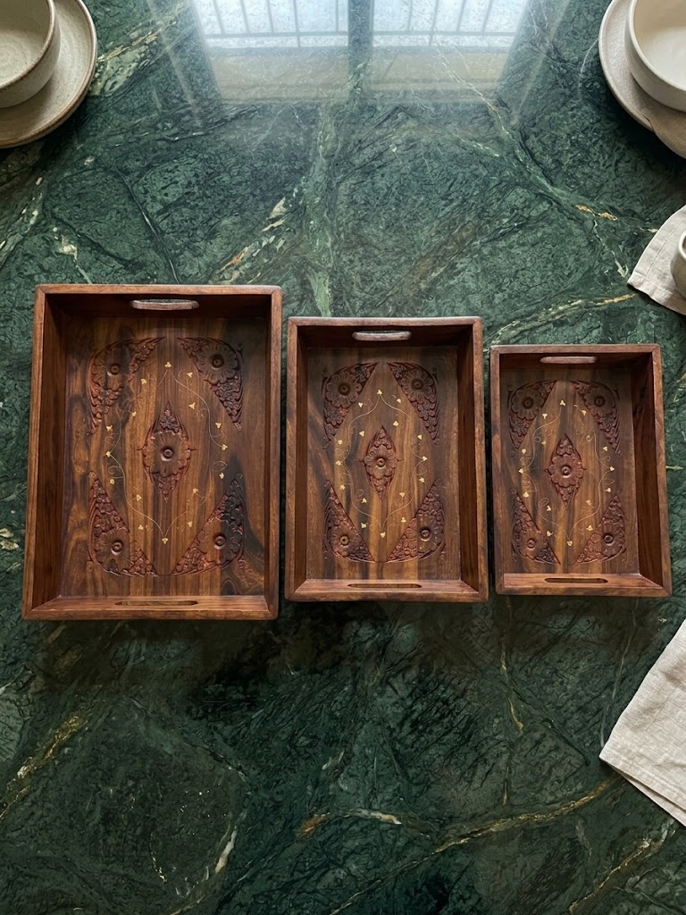 Set of 3 hand-carved wooden serving trays with gold inlay on green marble surface